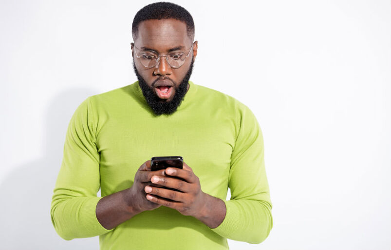 A surprised and shocked man looking at his cellphone