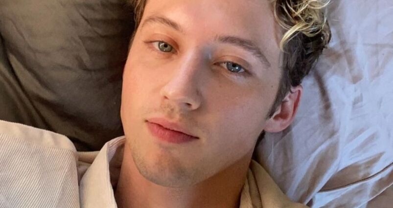 Troye Sivan staring into the camera with blonde highlights. 