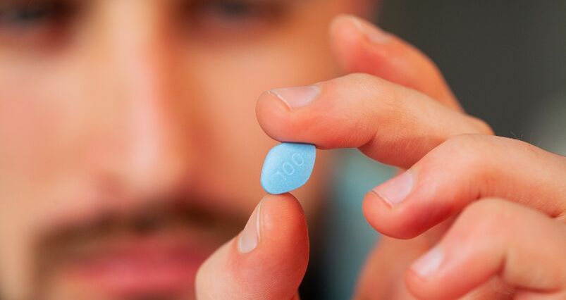 A man holds a Viagra pill