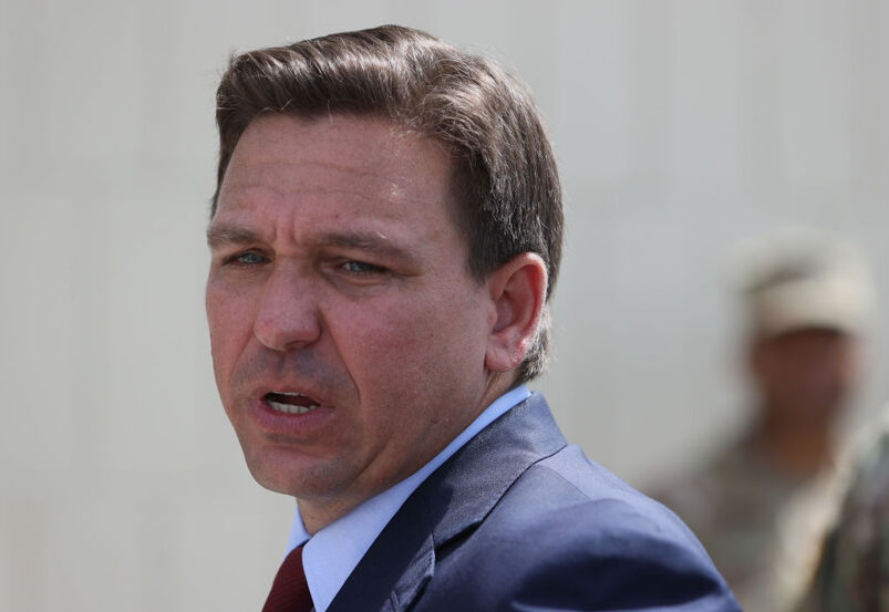 Ron DeSantis leaving a press conference in a suit and tie.