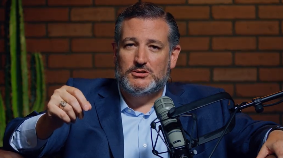 Ted Cruz in a blue suit speaking into a microphone.