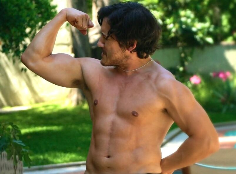 YouTuber Markiplier stands shirtless in a pool flexing his right bicep.