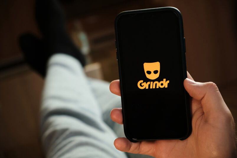 Picture of an iPhone with the yellow Grindr logo. 