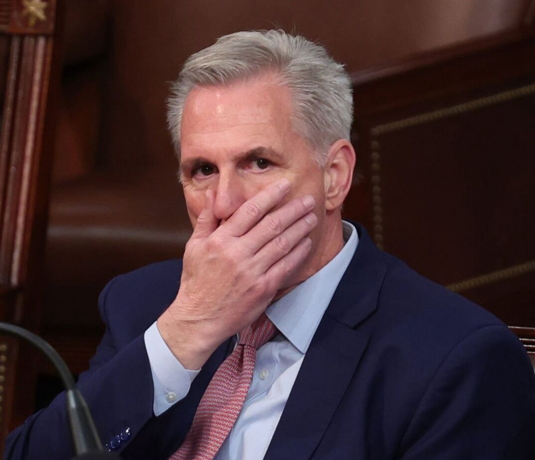 Kevin McCarthy sitting in the House Chamber with his hand over his mouth. 