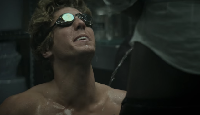 Lukas Gage in a kinky scene from episode 2, season 4, of the Netflix series YOU where he gets peed on by a staffer while shirtless wearing goggles
