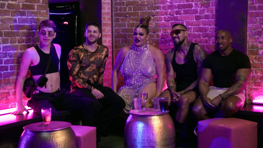 "Hot Haus" judges look on in a neon-lit room with a brick wall behind them.