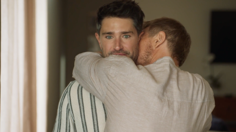 Two men embrace. We see one's eyes wide-open, as if he wasn't expecting the hug.
