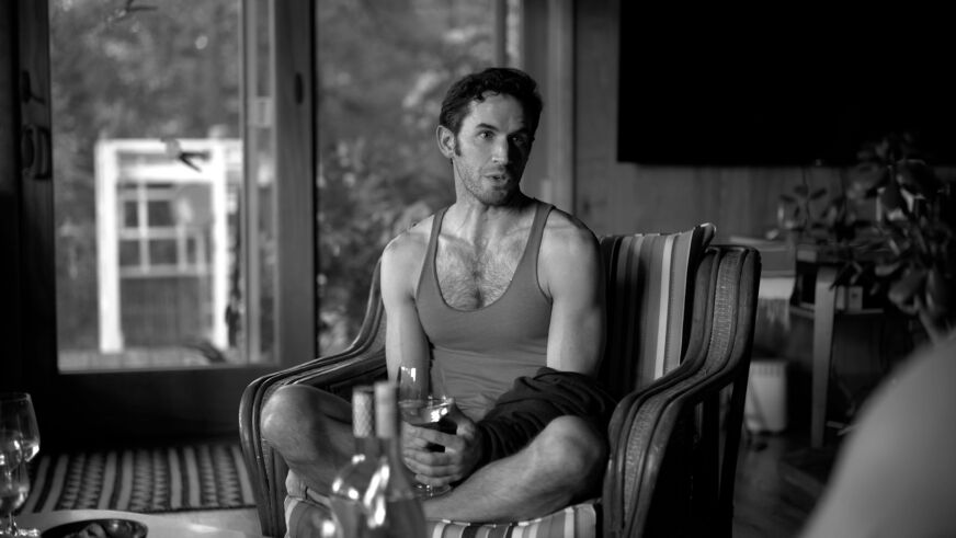 Wyatt Fenner ears a tanktop in the middle of a living room in black-and-white film 'Chrissy Judy'