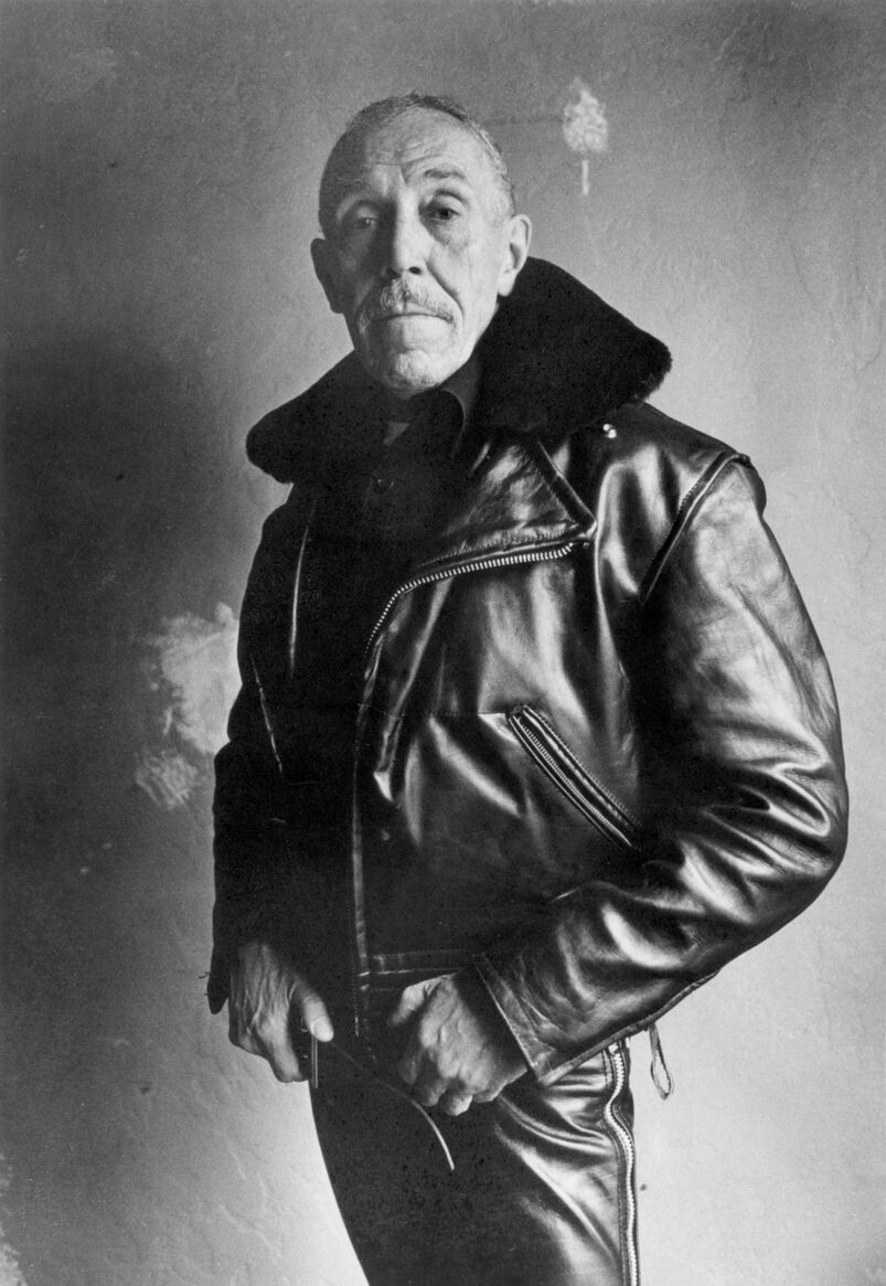 Tom of Finland wearing a leather jacket and holding a knife. 