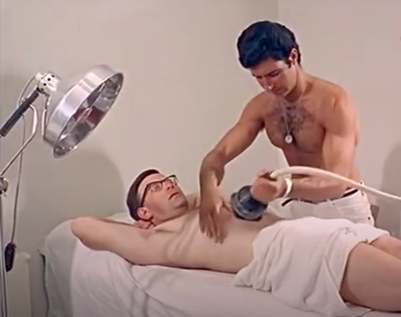 Shirtless man laying down on a massage table receiving a vibro massage.