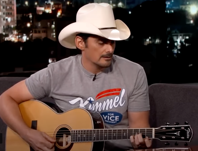 Brad Paisley in a white cowboy hat playing a guitar