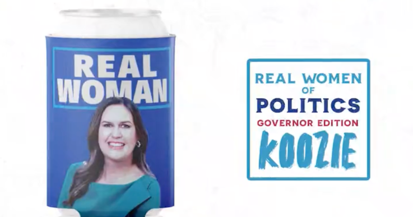Sarah Huckabee Sanders on a blue beer koozie featuring the words "Real Woman"