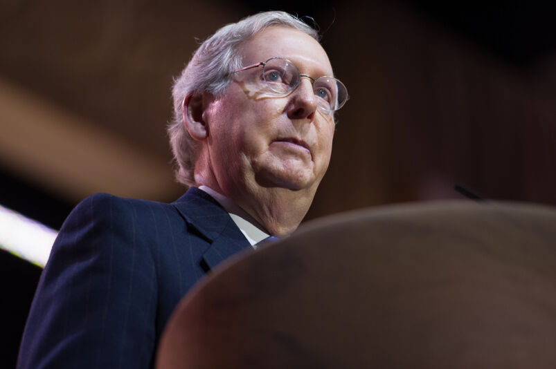Close up of Mitch McConnell standing behind a podium wearing a dark suit jacket. 
