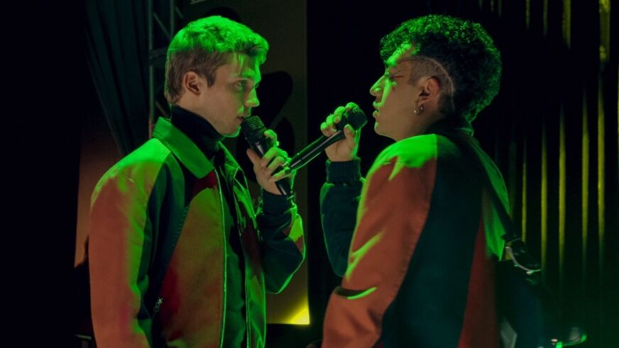 Two stars of Netflix's Rebelde sing to each other while bathed in green light