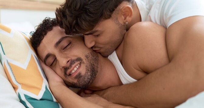Two men cuddle in bed
