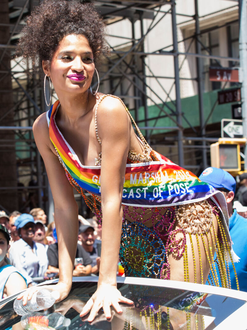 Actress Indya Moore, in a sparkly dress and rainbow Grand Marshal sash, dances on top of a car at the 2019 New York Pride Parade.