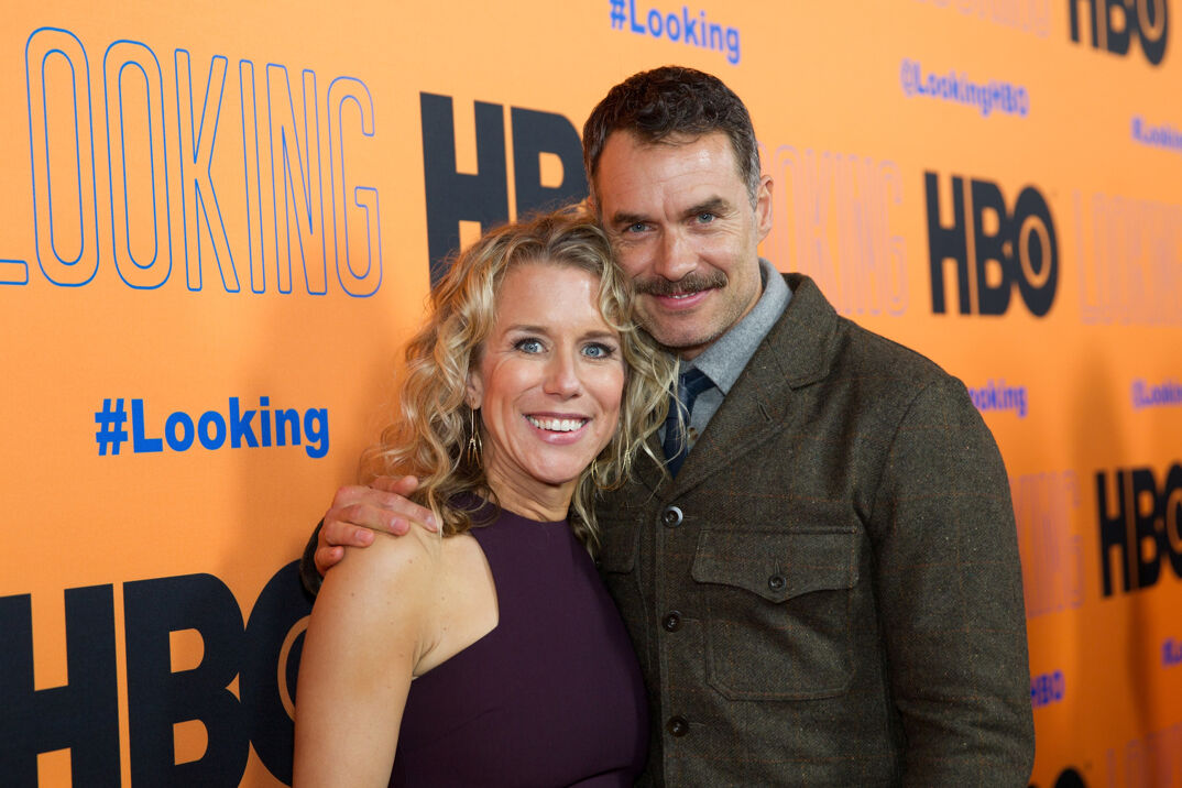 Lauren Weedman and Murray Bartlett smile with their arms around each other on the red carpet.