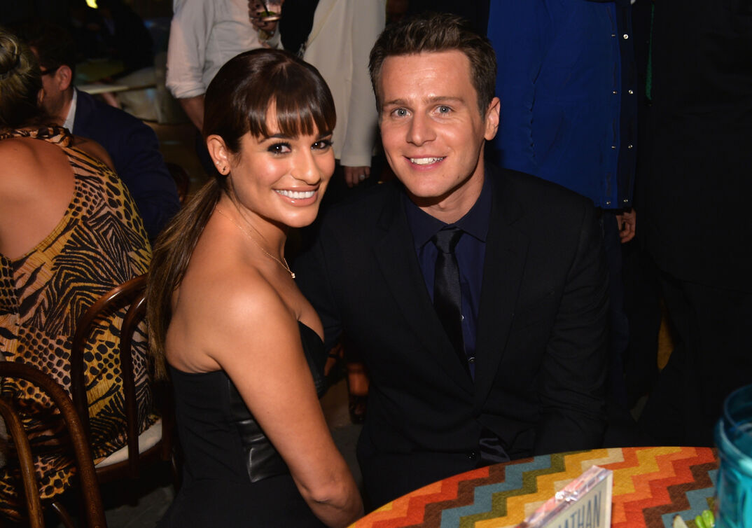 Lea Michele and Jonathan Groff sitting a table smiling.