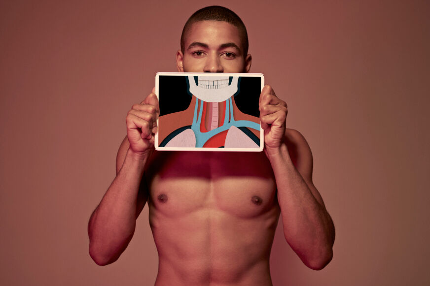 Male holding tablet in front of body to display coloured x-ray illustrations made out of hand made paper structures