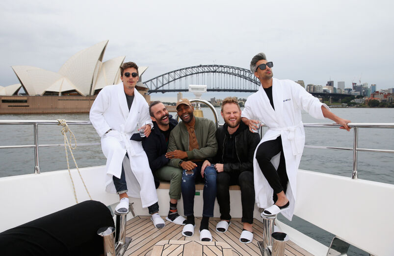 Antoni Porowski, Jonathan Van Ness, Karamo Brown, Bobby Berk, and Tan France laugh and smile wearing white flip flops on a boat, with the Sydney Opera House behind them.