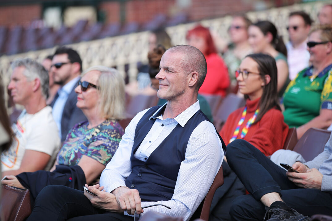 Former rugby player Ian Roberts sitting in a light blue dress shirt and dark blue vest.