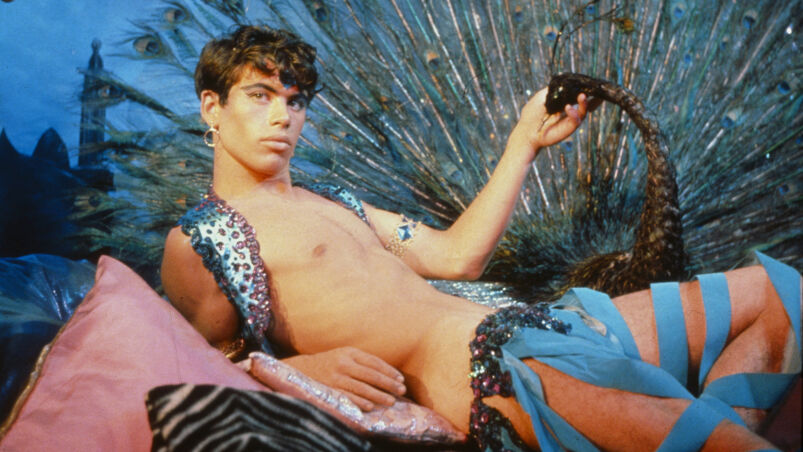 A still from 'Pink Narcissus' featuring a call-boy in blue and peacock feathers