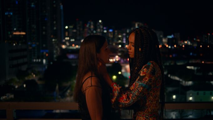 A still from the film 'Jagged Mind,' featuring two women about to kiss with the skyline behind them.