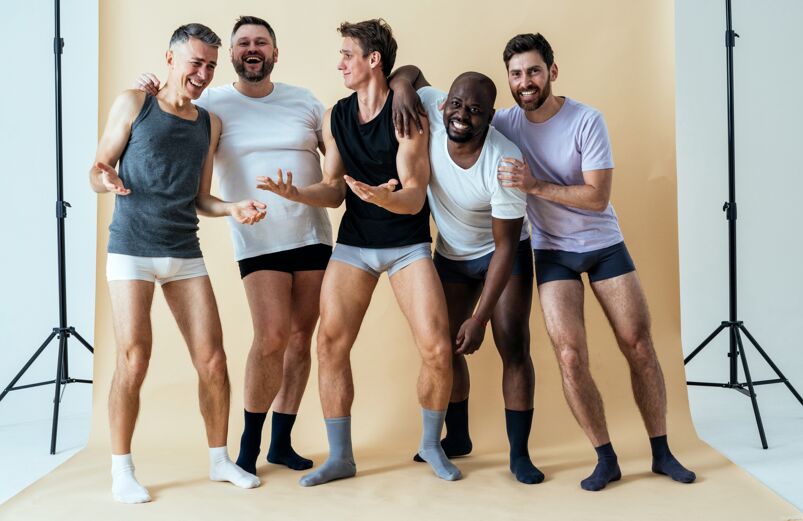 Happy young men of different body types standing together in underwear