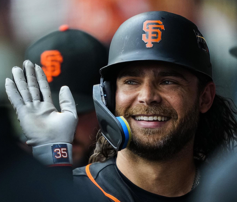 San Francisco Giants player Brandon Crawford smiling and wearing his helmet in the dugout.