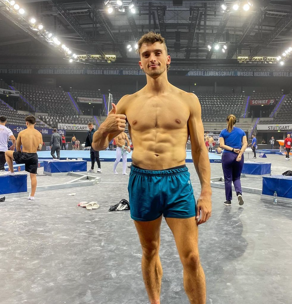 Australian gymnast Heath Thorpe standing shirtless with a big thumbs up into the camera.