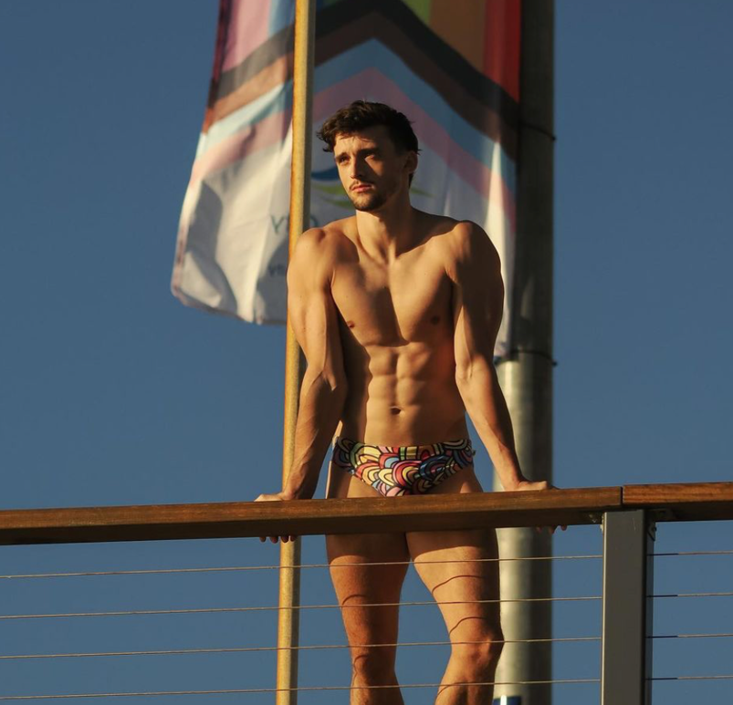 Heath Thorpe standing shirtless in front of the Progress Flag.