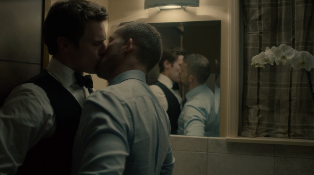 Jonathan Groff and Russell Tovey kiss up against a bathroom wall.