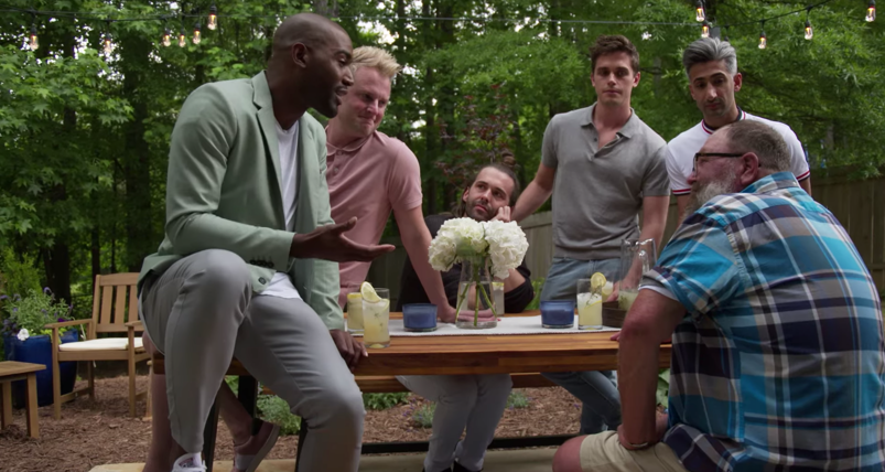 Karamo Brown, Bobby Berk, Jonathan Van Ness, Antoni Porowoski, and Tan France sit at an outdoor picnic table talking to Tom Jackson in an episode of 'Queer Eye.'