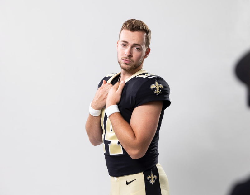 Jake Haener posing in a New Orleans Saints jersey.