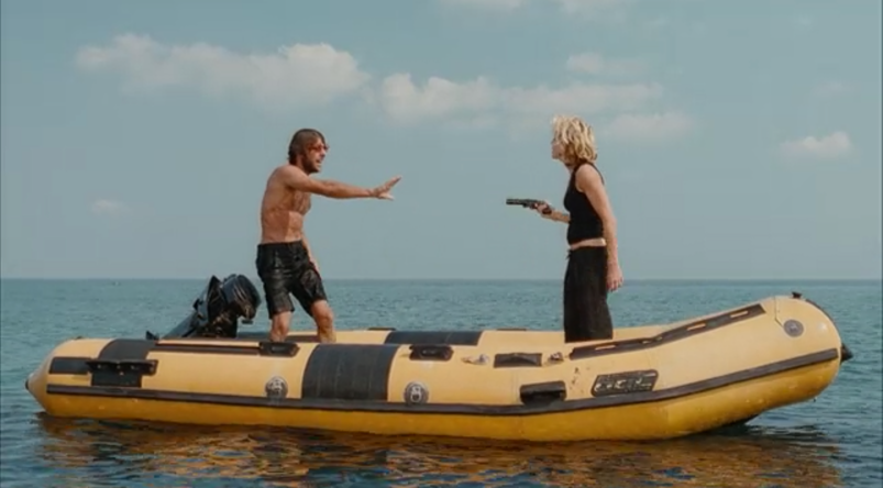 A shirtless Adriano Giannini stands with his hands up as Madonna holds up a flare gun on a dingy in the middle of the ocean in 'Swept Away.'