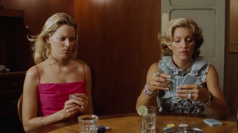 Elizabeth Banks, wearing a pink low cut dress, looks perturbed as she plays cards next to Madonna, who's concentrated on winning, in a scene from 'Swept Away.'