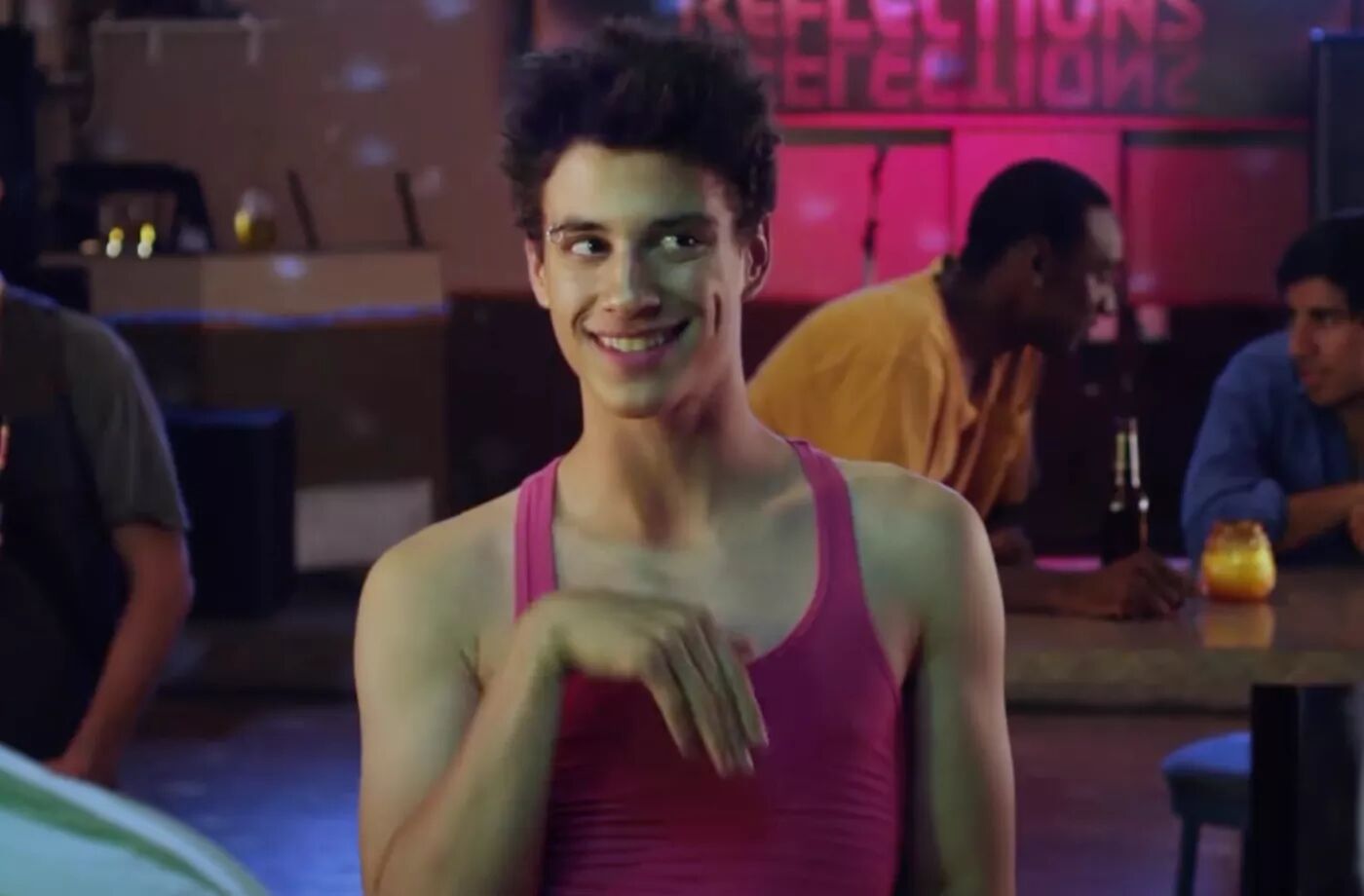 Actor Adam DiMarco stands in a gay club wearing a pink tank top, showing off his limp wrist in 2014 film 'Date and Switch.'
