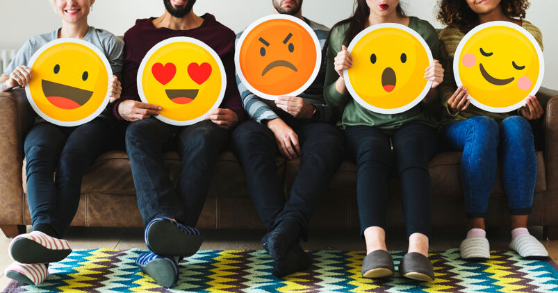 5 people sitting on a couch holding different emojis. 