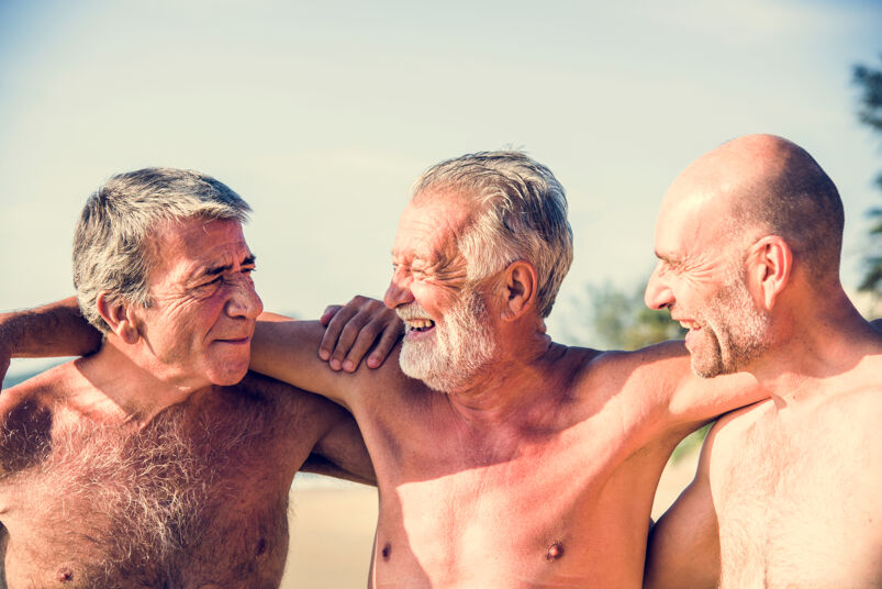 Three elderly white men hugging. 