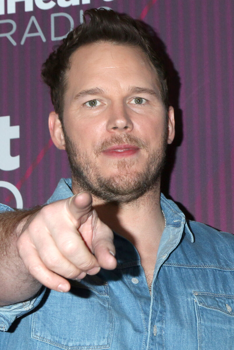 A close-up of Chris Pratt pointing at the camera in a denim shirt. 