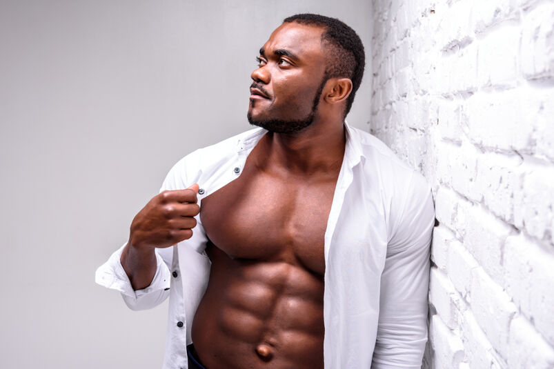 Muscular Black man with his white shirt unbuttoned and looking to the side. 