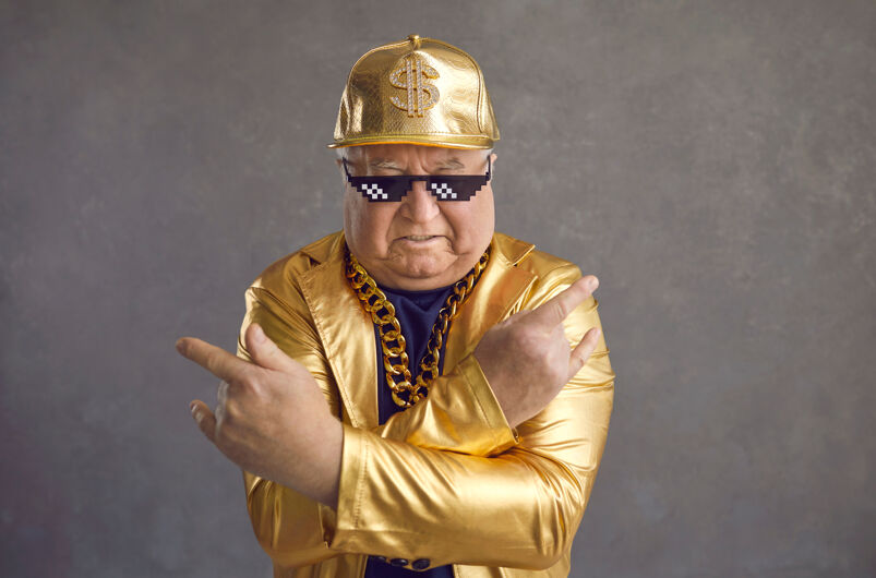 Elderly man dressed like a gangster in gold. 