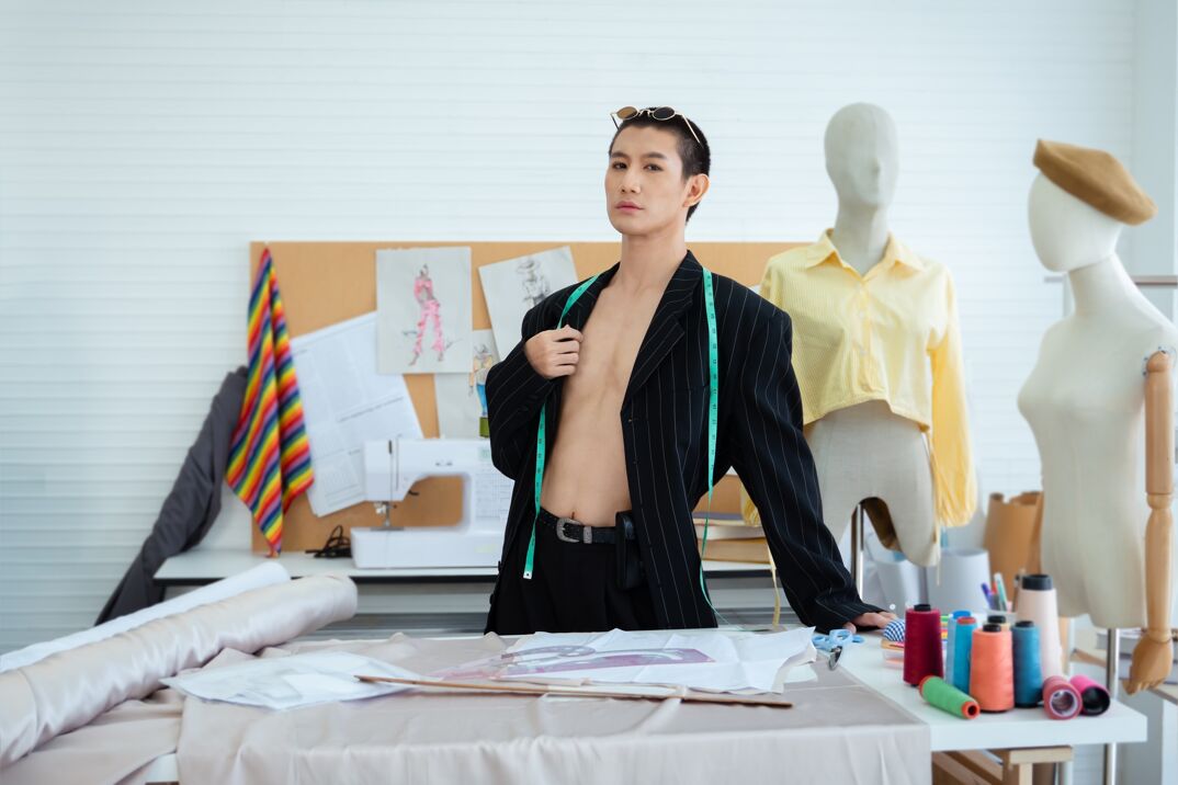 A man posing in front of a fashion work station. 