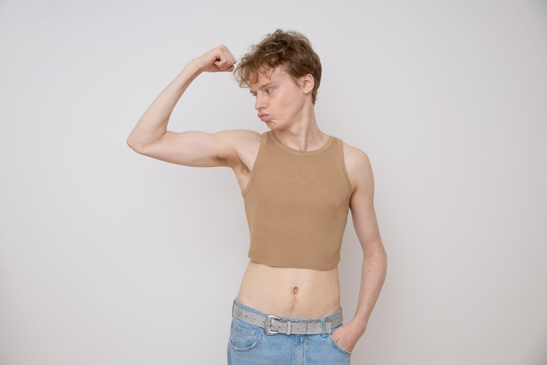 Young man flexing and wearing crop tank top. 