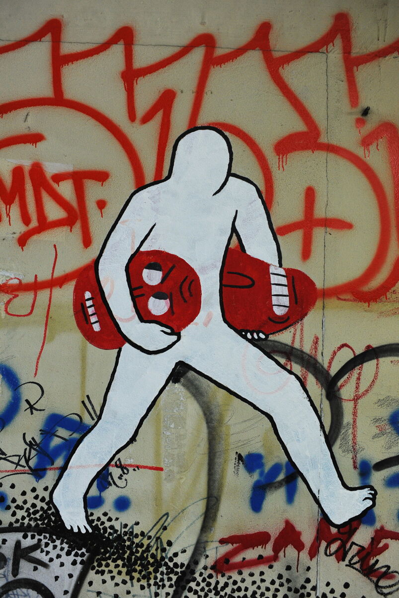 Graffiti of a white figure holding two  red heads by Keith Haring. 