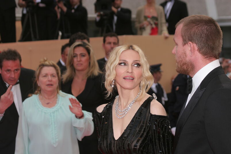 Madonna looks at Guy Ritchie while walking down the red carpet. Passerby watch them and wave.