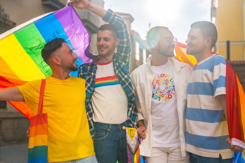 four gay male-presenting people demonstrating what to wear to Pride events