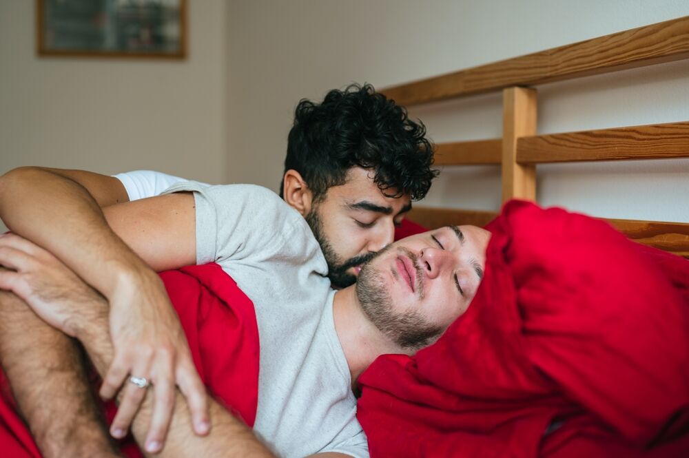 Gay couple snuggling in bed