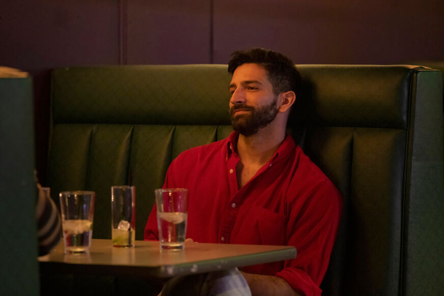 Kris Kelkar sits at a bar in a red shirt in 'Swiping America'