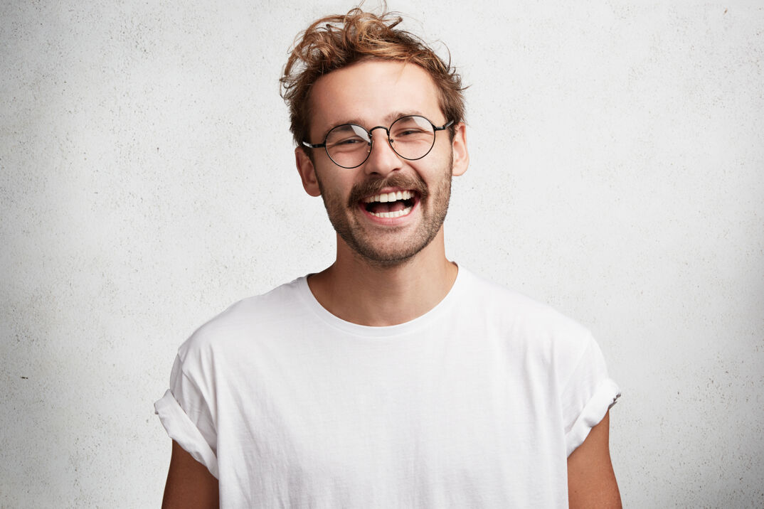 Attractive man smiling with glasses and a mustache.